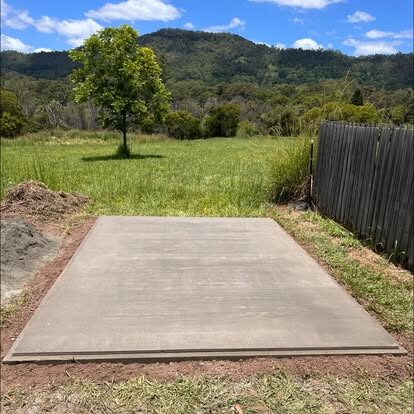 A freshly poured, neatly edged shed slab in a green paddock near Kyogle with hills behind
