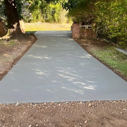 A fresh, smooth concrete driveway curving up to a home, framed by trees